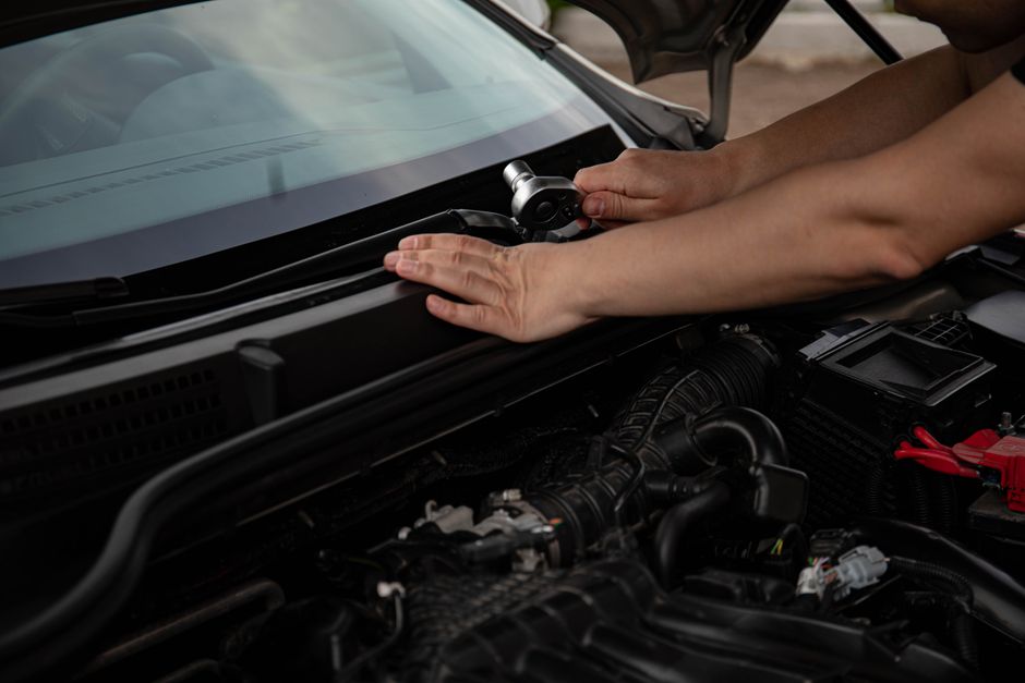 Close-up of a mechanic using a ratchet tool on a car engine in an auto repair shop.